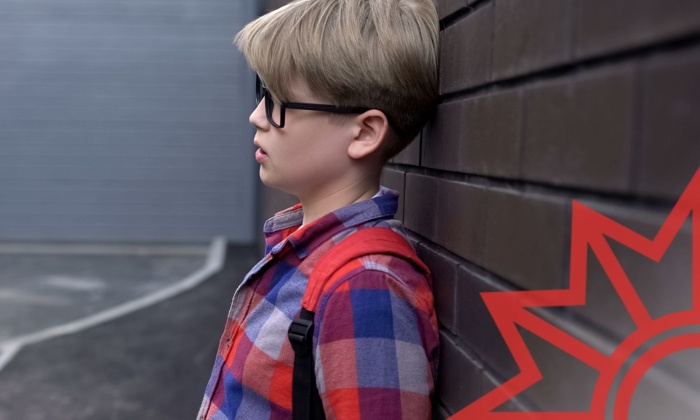 Junge mit Brille lehnt draußen an der Wand